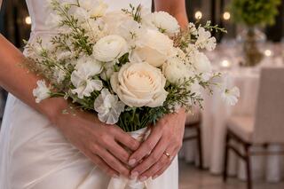 A bouquet of delicate white roses and blooms, elegantly held by a bride in a satin gown, exuding romance and timeless beauty.