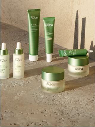 A collection of skincare products in green packaging arranged on a textured surface, showcasing a fresh and natural aesthetic.