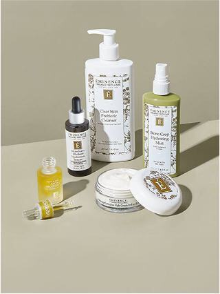 A collection of skincare products featuring cleansers, a hydrating mist, serum, and moisturizer, all elegantly arranged on a neutral background.