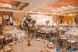 Elegant banquet hall adorned with floral centerpieces, golden accents, and inviting lighting, perfect for a luxurious event or celebration.