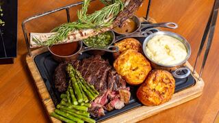 A platter features juicy steak, tender asparagus, creamy mashed potatoes, and savory sides, garnished with fresh rosemary and sauces.