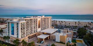 Three women perform side stretches outdoors, wearing athletic clothing, with a background of trees and a sunset, promoting wellness and fitness.