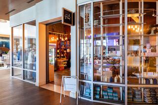 A chic retail space features glass walls, inviting entrance, and displays of products, creating an enticing atmosphere for shoppers.