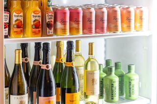 A fridge filled with assorted beverages: fruity juices, sparkling wines, and colorful canned cocktails, creating a vibrant, inviting display.