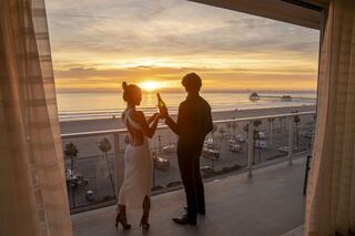 A couple toasts at sunset with a stunning ocean view, radiating romance and celebration in a beautiful setting.