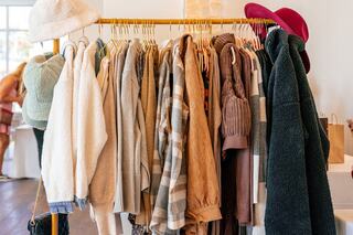 A colorful rack displays a variety of cozy apparel, including sweaters and hats, in a bright, inviting boutique setting.