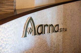 A stylish spa reception area features the name "Anna SPA" in an elegant font against a textured, calming backdrop.