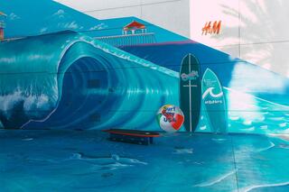 A vibrant mural features a large wave, surfboards, and beach elements, creating a lively coastal scene with playful dolphins.