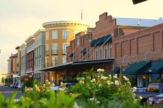 Charming street in downtown Napa, CA lined with historic brick and modern buildings, featuring lush floral landscaping and welcoming storefronts.