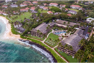 A coastal resort features lush greenery, sandy beaches, and colorful buildings, set against a serene ocean backdrop. Relaxation awaits.