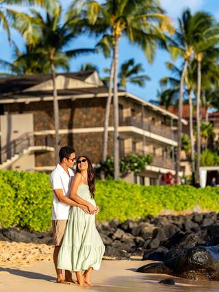 A couple enjoys a sunny beach, smiling and embracing among palm trees and ocean waves, exuding joy and warmth in a tropical setting.