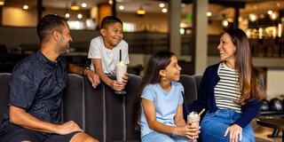 A family enjoys ice cream and milkshakes while sharing smiles and laughter in a cozy, modern setting.