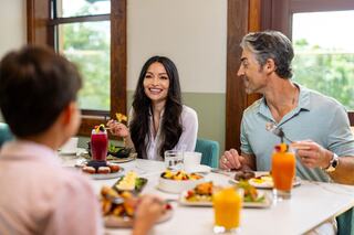 A family enjoys a vibrant meal together, sharing laughter and delicious food, with colorful drinks on the table and a cheerful atmosphere.