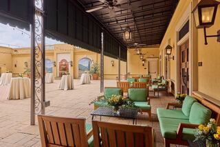 A cozy outdoor seating area features green chairs, wooden tables, and elegant decor, perfect for gatherings or events.