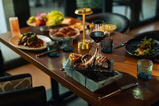 A beautifully arranged dining table featuring a variety of gourmet dishes, elegant glassware, and soft lighting, creating a warm atmosphere.