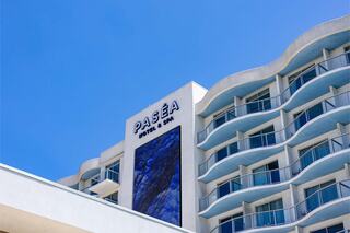 A modern hotel with a sleek design featuring curved balconies and a large digital display against a clear blue sky.