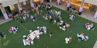 A vibrant outdoor gathering with guests socializing, dining, and enjoying a lively atmosphere amidst decorations and soft lighting.