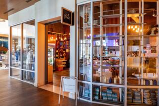 A modern retail space features large glass windows, showcasing an inviting shop with colorful products and stylish decor.