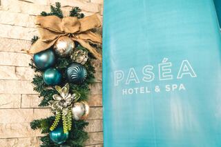 A festive arrangement of teal and silver ornaments, accented with greenery and a bow, next to a sign for Paséa Hotel & Spa.