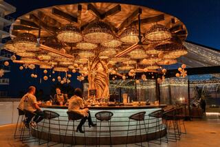 A bartender creates cocktails, featuring a festive atmosphere with a Santa hat on the bar, showcasing artistry and vibrant drinks.