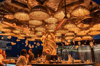 A bartender creates cocktails, featuring a festive atmosphere with a Santa hat on the bar, showcasing artistry and vibrant drinks.