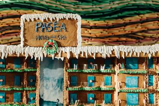 A whimsical gingerbread hotel and spa, complete with festive decorations, colorful icing, and detailed windows depicting a waterfall.