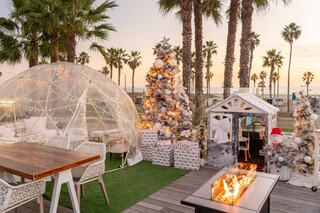 Cozy outdoor seating with transparent domes, festive lights, and a fire pit, creating a warm atmosphere for relaxation and socializing.