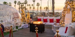 Cozy outdoor seating with transparent domes, festive lights, and a fire pit, creating a warm atmosphere for relaxation and socializing.