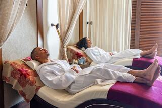 A man and woman relax side by side in cozy robes, enjoying a peaceful moment in a serene spa setting.