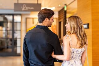 A couple walks closely together, smiling and enjoying each other's company in a stylish indoor setting.