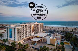 A beachfront hotel with palm trees, ocean views, and a promotional badge for Travel + Leisure's World's Best Awards 2026.
