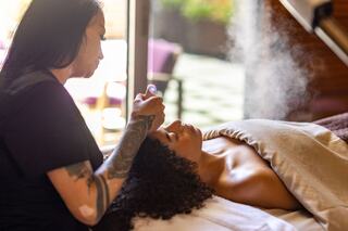 A professional applies a soothing treatment to a client's face, as steam rises softly in a serene spa setting. Relaxation is palpable.
