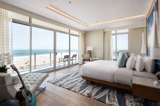 Stylish beachside hotel room with ocean views, featuring a plush bed, modern decor, and a cozy seating area, perfect for relaxation.